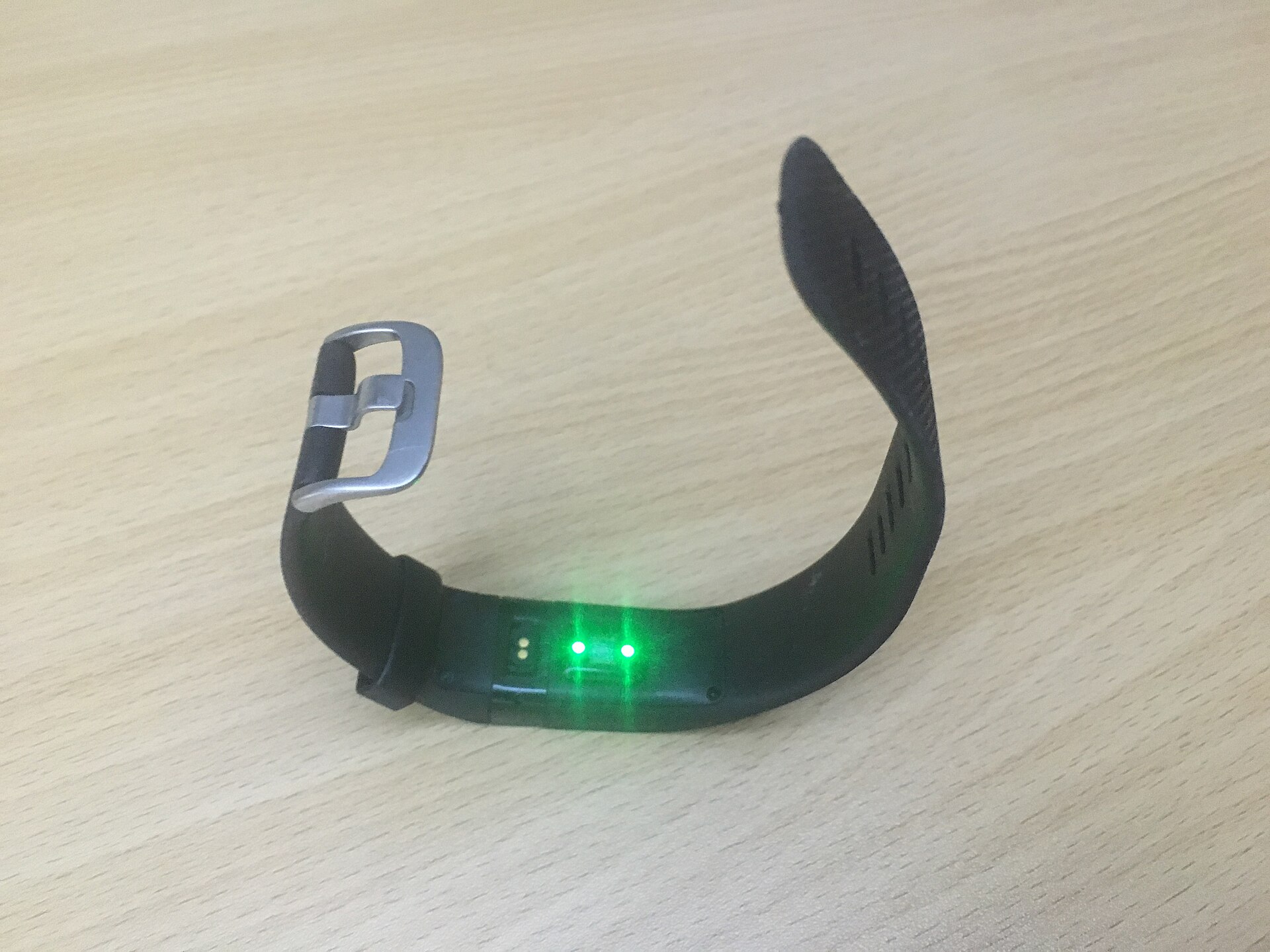 A sleep tracker charging on a wooden nightstand beside a glowing amber nightlight late at night