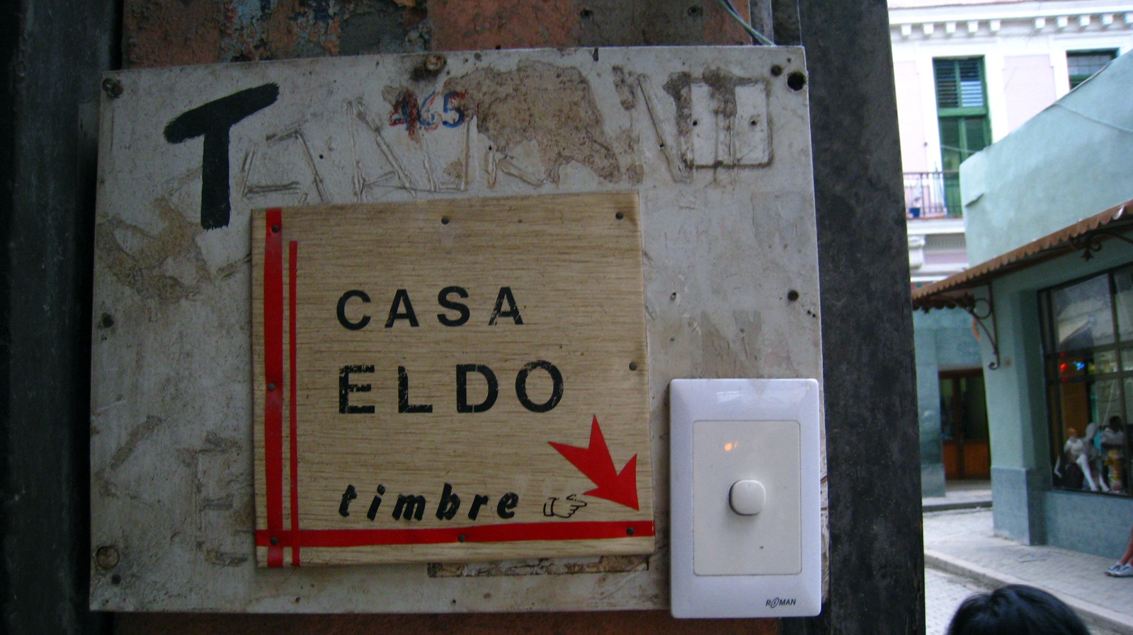 A compact battery video doorbell mounted on an apartment door frame above a package left on the mat