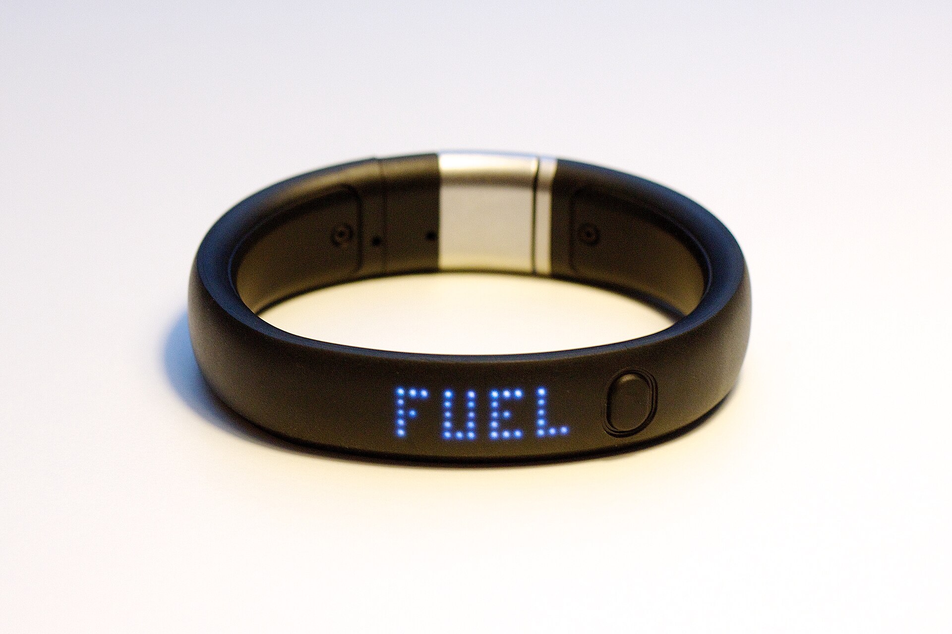 A runner checking a fitness band on their wrist on a park path at sunrise