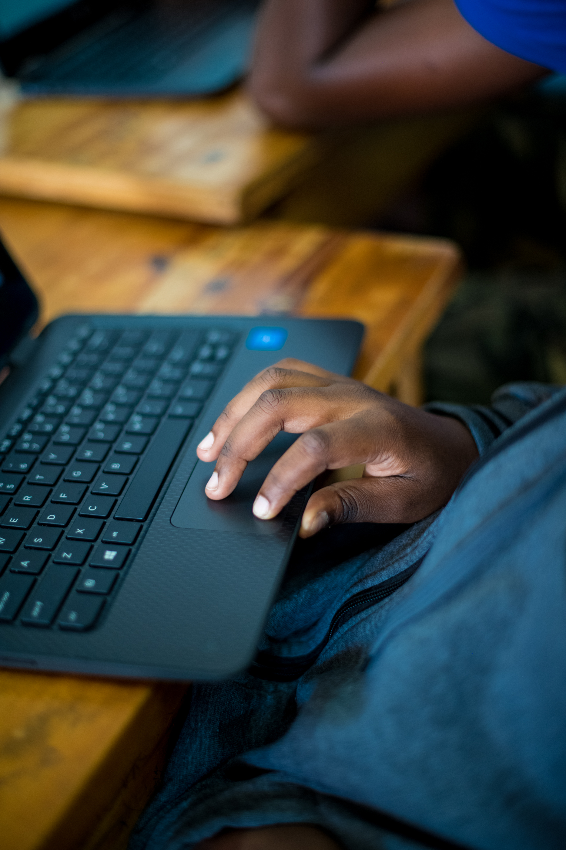 A buyer inspecting a refurbished laptop's screen and keyboard at a seller's counter in person
