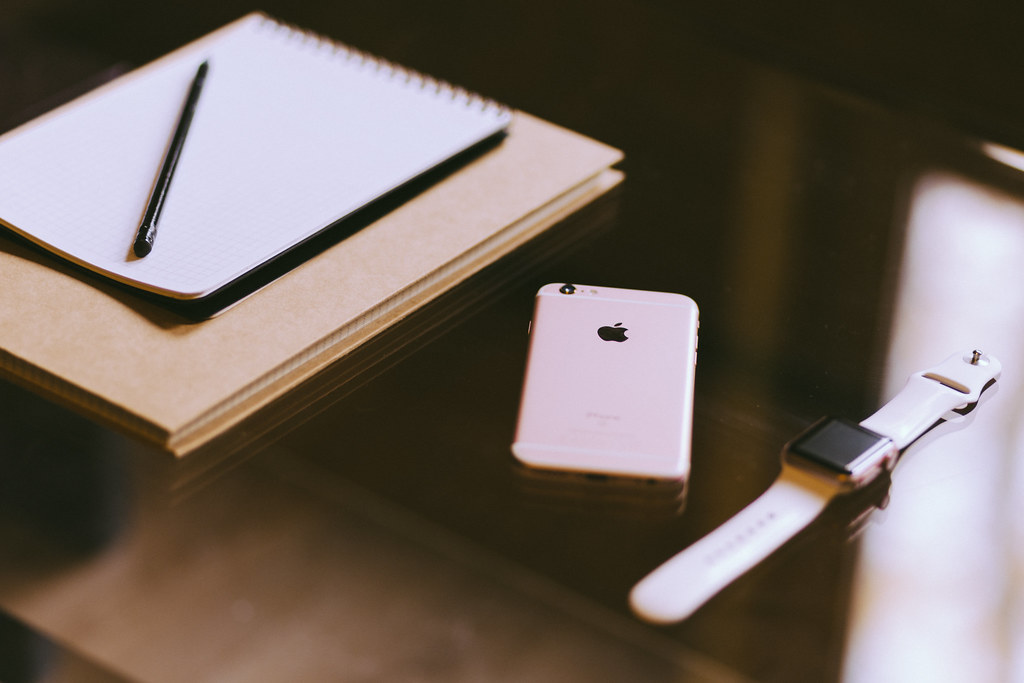 A smartphone and a smartwatch lying side by side on a wooden desk during pairing